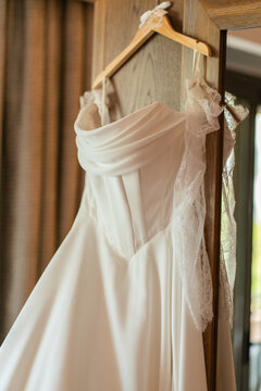 Wedding dress hanging in a room with natural light coming through the window