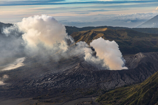 Mount Bromo volcano at sunrise, viewed from King Kong viewpoint in Bromo Tengger Semeru National Park, East Java, Indonesia. Active crater smoke, Mount Semeru cone, clouds, and vast ash plain.