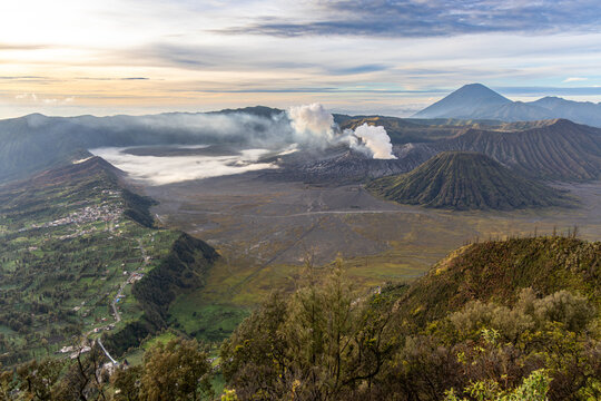 Mount Bromo volcano at sunrise, viewed from King Kong viewpoint in Bromo Tengger Semeru National Park, East Java, Indonesia. Active crater smoke, Mount Semeru cone, clouds, and vast ash plain.