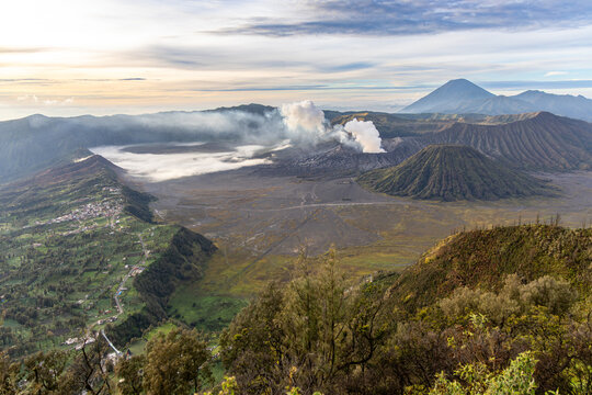 Mount Bromo volcano at sunrise, viewed from King Kong viewpoint in Bromo Tengger Semeru National Park, East Java, Indonesia. Active crater smoke, Mount Semeru cone, clouds, and vast ash plain.