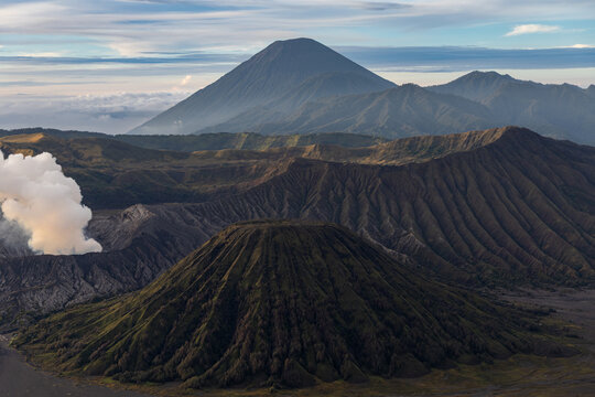 Mount Bromo volcano at sunrise, viewed from King Kong viewpoint in Bromo Tengger Semeru National Park, East Java, Indonesia. Active crater smoke, Mount Semeru cone, clouds, and vast ash plain.