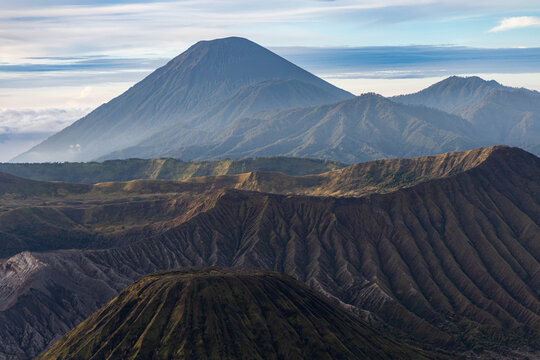 Mount Bromo volcano at sunrise, viewed from King Kong viewpoint in Bromo Tengger Semeru National Park, East Java, Indonesia. Active crater smoke, Mount Semeru cone, clouds, and vast ash plain.