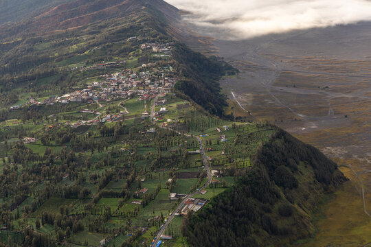Mount Bromo volcano at sunrise, viewed from King Kong viewpoint in Bromo Tengger Semeru National Park, East Java, Indonesia. Active crater smoke, Mount Semeru cone, clouds, and vast ash plain.