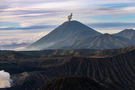 Mount Bromo volcano at sunrise, viewed from King Kong viewpoint in Bromo Tengger Semeru National Park, East Java, Indonesia. Active crater smoke, Mount Semeru cone, clouds, and vast ash plain.