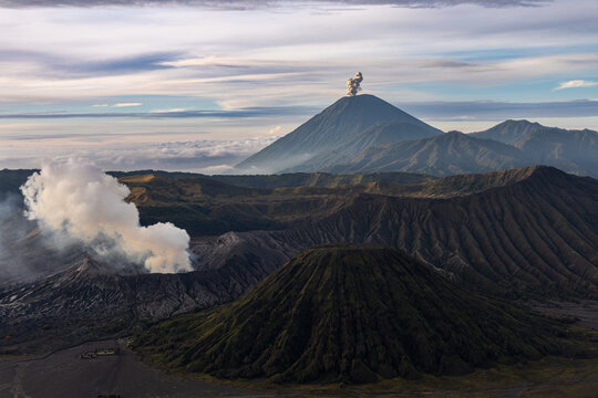 Mount Bromo volcano at sunrise, viewed from King Kong viewpoint in Bromo Tengger Semeru National Park, East Java, Indonesia. Active crater smoke, Mount Semeru cone, clouds, and vast ash plain.