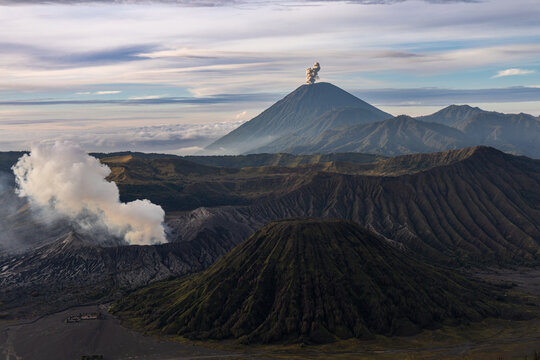 Mount Bromo volcano at sunrise, viewed from King Kong viewpoint in Bromo Tengger Semeru National Park, East Java, Indonesia. Active crater smoke, Mount Semeru cone, clouds, and vast ash plain.