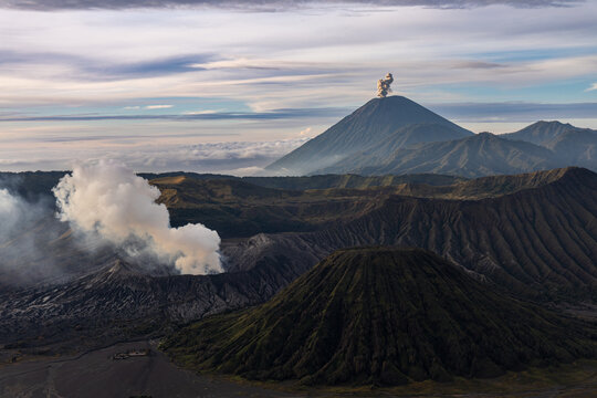 Mount Bromo volcano at sunrise, viewed from King Kong viewpoint in Bromo Tengger Semeru National Park, East Java, Indonesia. Active crater smoke, Mount Semeru cone, clouds, and vast ash plain.