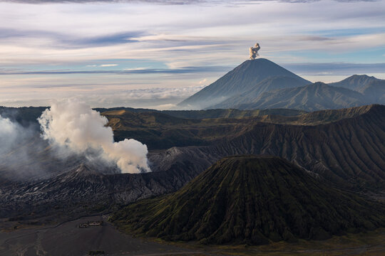 Mount Bromo volcano at sunrise, viewed from King Kong viewpoint in Bromo Tengger Semeru National Park, East Java, Indonesia. Active crater smoke, Mount Semeru cone, clouds, and vast ash plain.