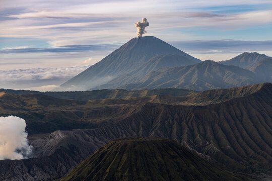 Mount Bromo volcano at sunrise, viewed from King Kong viewpoint in Bromo Tengger Semeru National Park, East Java, Indonesia. Active crater smoke, Mount Semeru cone, clouds, and vast ash plain.