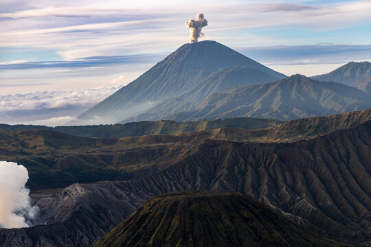 Mount Bromo volcano at sunrise, viewed from King Kong viewpoint in Bromo Tengger Semeru National Park, East Java, Indonesia. Active crater smoke, Mount Semeru cone, clouds, and vast ash plain.