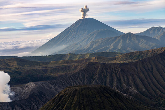 Mount Bromo volcano at sunrise, viewed from King Kong viewpoint in Bromo Tengger Semeru National Park, East Java, Indonesia. Active crater smoke, Mount Semeru cone, clouds, and vast ash plain.