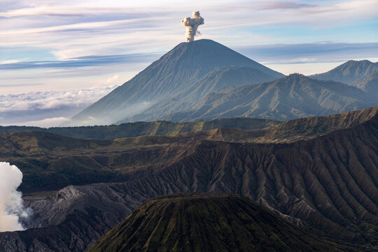 Mount Bromo volcano at sunrise, viewed from King Kong viewpoint in Bromo Tengger Semeru National Park, East Java, Indonesia. Active crater smoke, Mount Semeru cone, clouds, and vast ash plain.