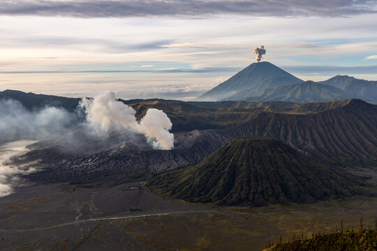 Mount Bromo volcano at sunrise, viewed from King Kong viewpoint in Bromo Tengger Semeru National Park, East Java, Indonesia. Active crater smoke, Mount Semeru cone, clouds, and vast ash plain.