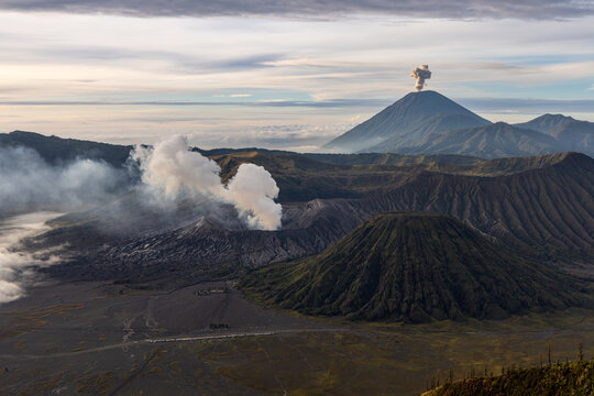 Mount Bromo volcano at sunrise, viewed from King Kong viewpoint in Bromo Tengger Semeru National Park, East Java, Indonesia. Active crater smoke, Mount Semeru cone, clouds, and vast ash plain.