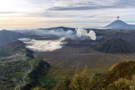 Mount Bromo volcano at sunrise, viewed from King Kong viewpoint in Bromo Tengger Semeru National Park, East Java, Indonesia. Active crater smoke, Mount Semeru cone, clouds, and vast ash plain.