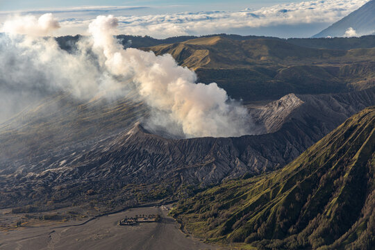 Mount Bromo volcano at sunrise, viewed from King Kong viewpoint in Bromo Tengger Semeru National Park, East Java, Indonesia. Active crater smoke, Mount Semeru cone, clouds, and vast ash plain.