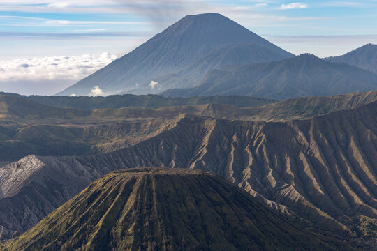 Mount Bromo volcano at sunrise, viewed from King Kong viewpoint in Bromo Tengger Semeru National Park, East Java, Indonesia. Active crater smoke, Mount Semeru cone, clouds, and vast ash plain.