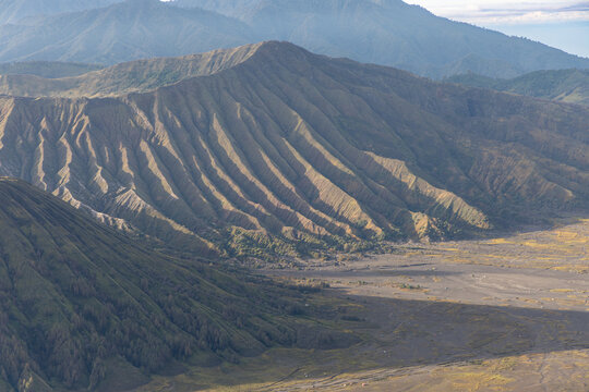 Mount Bromo volcano at sunrise, viewed from King Kong viewpoint in Bromo Tengger Semeru National Park, East Java, Indonesia. Active crater smoke, Mount Semeru cone, clouds, and vast ash plain.