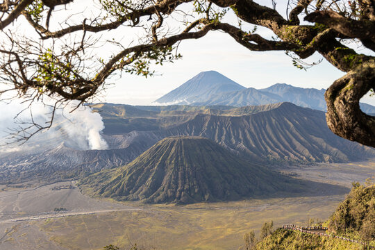 Mount Bromo volcano at sunrise, viewed from King Kong viewpoint in Bromo Tengger Semeru National Park, East Java, Indonesia. Active crater smoke, Mount Semeru cone, clouds, and vast ash plain.