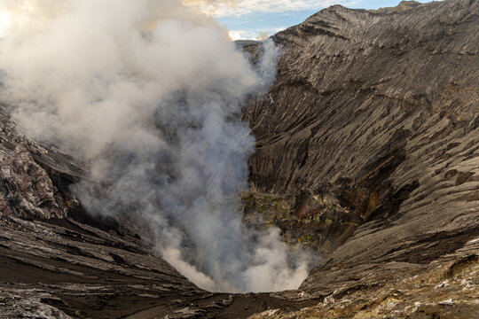 Active Mount Bromo volcano crater with sulfur smoke and volcanic sand sea, Tengger Semeru National Park, East Java, Indonesia.