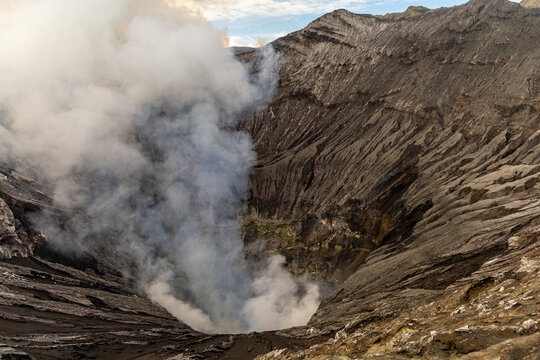 Active Mount Bromo volcano crater with sulfur smoke and volcanic sand sea, Tengger Semeru National Park, East Java, Indonesia.