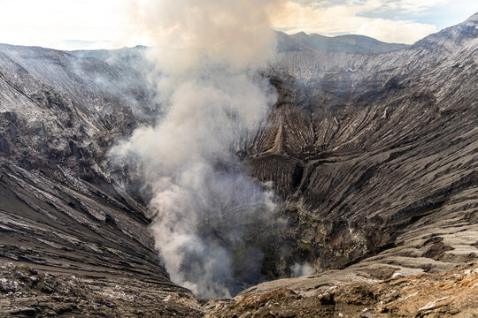 Active Mount Bromo volcano crater with sulfur smoke and volcanic sand sea, Tengger Semeru National Park, East Java, Indonesia.
