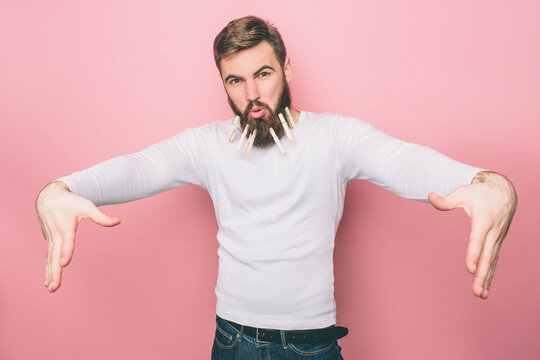 Funny guy is dansing with the closepins in his beard. H makes funny faces. Isolated on pink background.