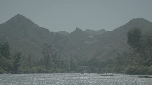 Softly lit mountain peaks behind trees and a dark valley floor