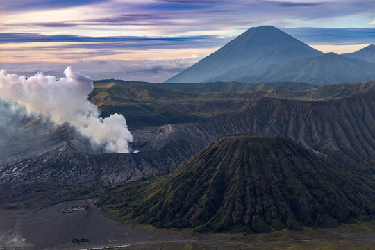 Mount Bromo volcano at sunrise, viewed from King Kong viewpoint in Bromo Tengger Semeru National Park, East Java, Indonesia. Active crater smoke, Mount Semeru cone, clouds, and vast ash plain.