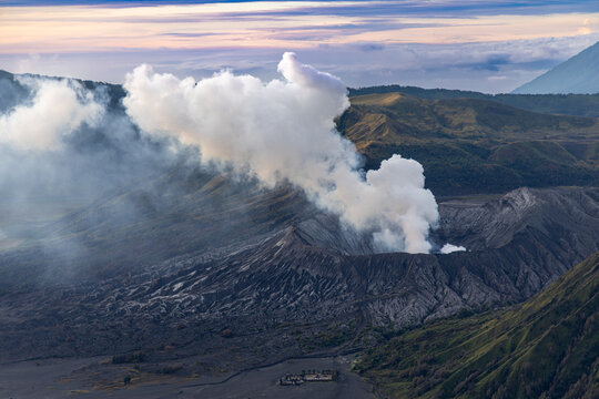 Mount Bromo volcano at sunrise, viewed from King Kong viewpoint in Bromo Tengger Semeru National Park, East Java, Indonesia. Active crater smoke, Mount Semeru cone, clouds, and vast ash plain.