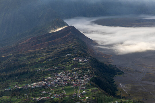 Mount Bromo volcano at sunrise, viewed from King Kong viewpoint in Bromo Tengger Semeru National Park, East Java, Indonesia. Active crater smoke, Mount Semeru cone, clouds, and vast ash plain.
