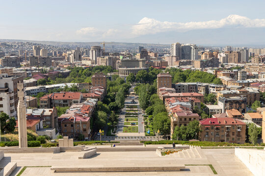 Aerial view from the Cascade over a tree lined avenue with flower gardens fountains and sculptures toward the opera house and city skyline on a clear summer day, Yerevan, Armenia