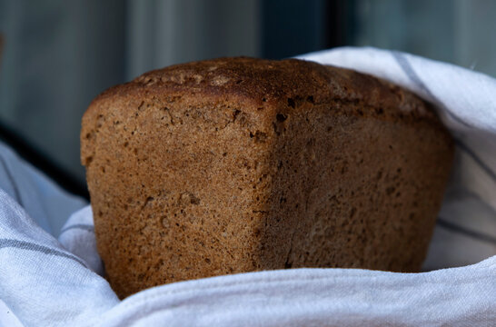 Whole grain sourdough bread loaf resting on a striped kitchen towel.