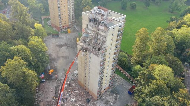 Aerial Drone view of a long arm excavator demolishing a 1960s tower block