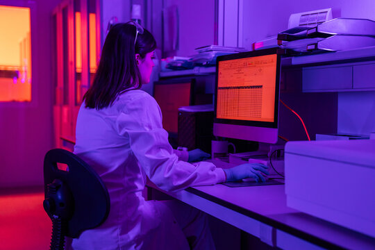 Woman Works at a Computer in a Laboratory With Colored Lights