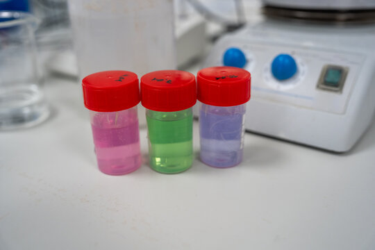 Three Small Bottles With Colorful Liquids Stand on a Laboratory Table