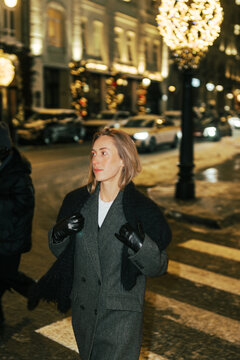 Person Walking on a City Street at Night During Winter Season