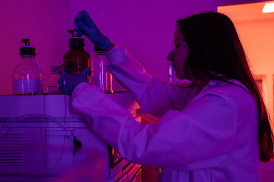 Scientist Working in a Laboratory With Purple Lighting in Evening