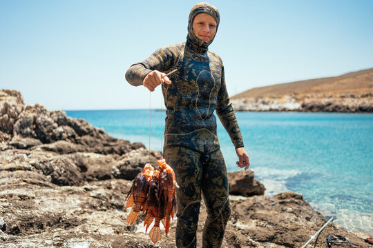 young spearfisher displaying invasive lionfish caught