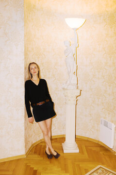 Model Poses Near a Statue and Lamp in a Vintage Room