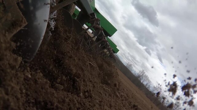 Tractor plough cutting soil, low angle view of field cultivation