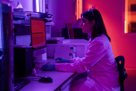 Scientist Working at Computer in Lab With Purple Lighting