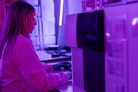 Scientist Working in a Lab With Purple Lighting and Computer Setup