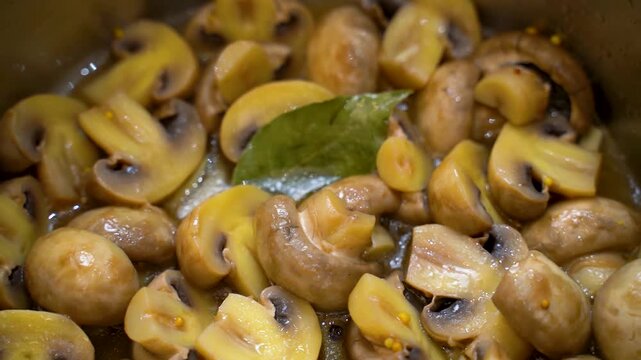 Marinated mushrooms with bay leaf in a saucepan, close-up