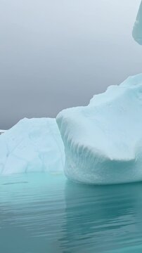 Vertical Video of Chunky White Icebergs on Blue-Green Water. White and blue ice, rippling water and soft diffuse light reveal natural frozen texture and sculpted contours across the marine scene.