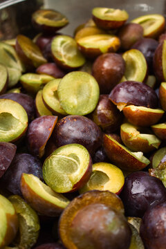 Plum halves background close up. Fresh ripe purple plums sliced in half without stones. Raw organic damson fruit ingredient for baking sweet pie, making homemade jam, autumn food harvest prune texture
