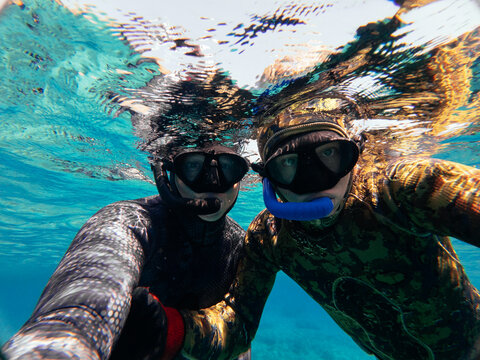 father and son taking selfie in clear mediterranean water