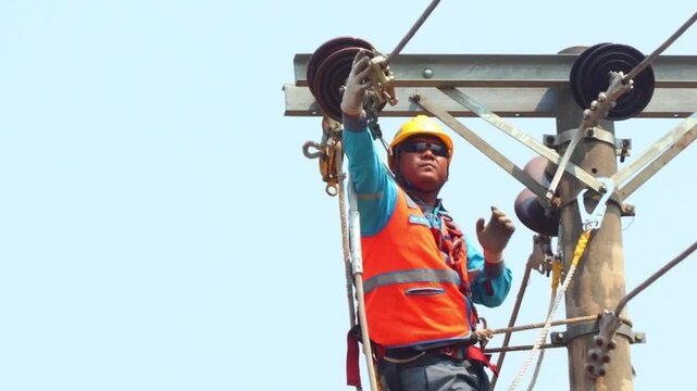 Electrician installing a hoist to pull cables on a three-phase power distribution line