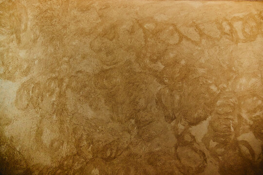 Textured golden-brown clay plaster wall with organic swirl patterns