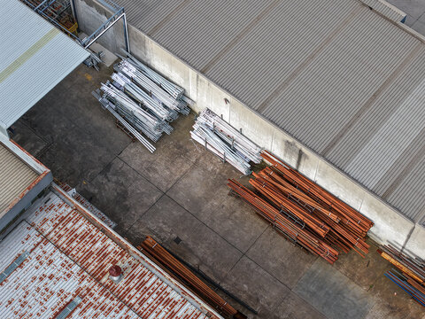 Aerial view of industrial site with stacks of metal pipes and materials stored between factory buildings in Melbourne, VIC, Australia.